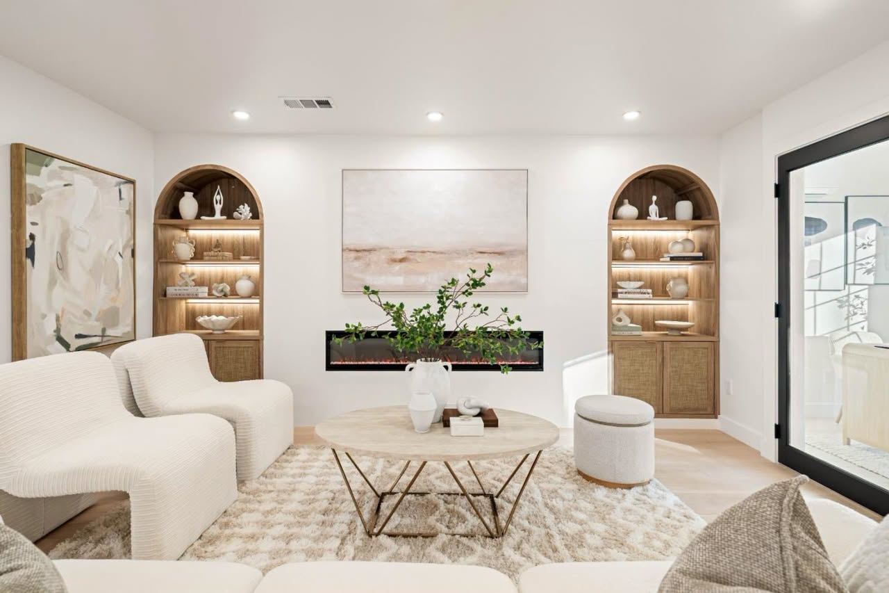 Living room with arched lit built-ins, boucle seating and linear fireplace styled by ONSTAGE